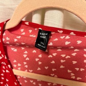 Red dress with white hearts and ruffles on the bottom part of dress.